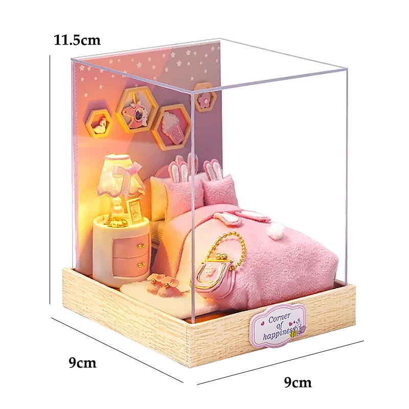 A clear acrylic miniature dollhouse featuring a pink bed, accessories, and decorative hexagonal elements.