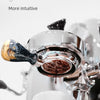A close-up view of a stainless steel bottomless espresso portafilter being used in a coffee machine.