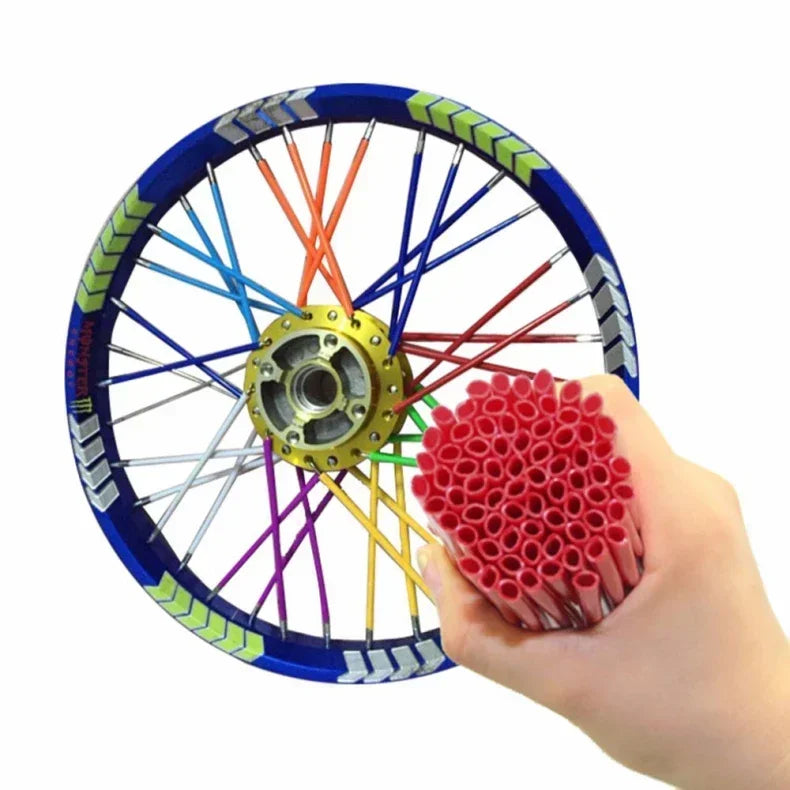 A hand holds a motorcycle wheel with colorful spokes and a red protective spoke cover kit.