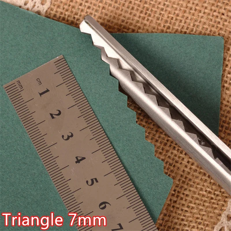A pair of silver triangle pinking shears resting on a green felt and a ruler.