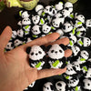 A hand holds a pile of handmade crochet kitten keychains featuring cute panda and cartoon animal charms.