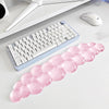 A pink bubble-shaped ergonomic wrist rest set for a keyboard and mouse is displayed on a white desk.
