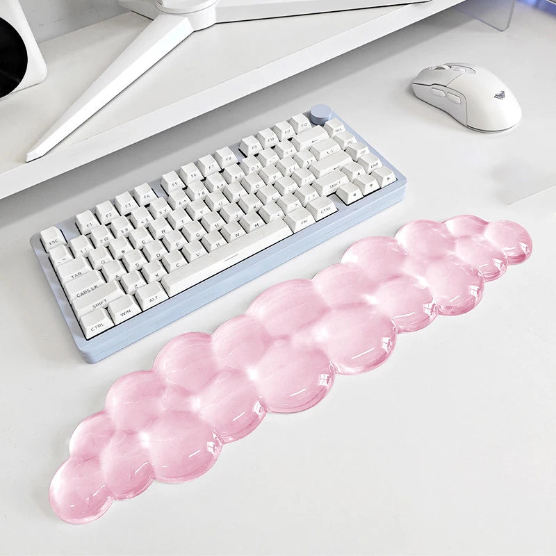 A pink bubble-shaped ergonomic wrist rest set for a keyboard and mouse is displayed on a white desk.