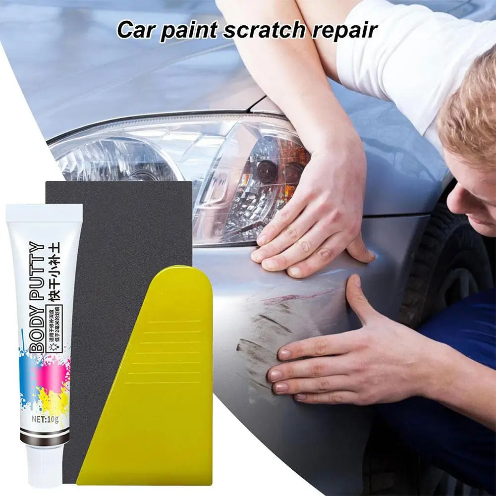 A hand is applying a yellow paste to repair a scratch on a car's paint surface.