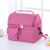 A pink insulated lunch bag with a zippered compartment and a separate pocket is shown on a white surface.
