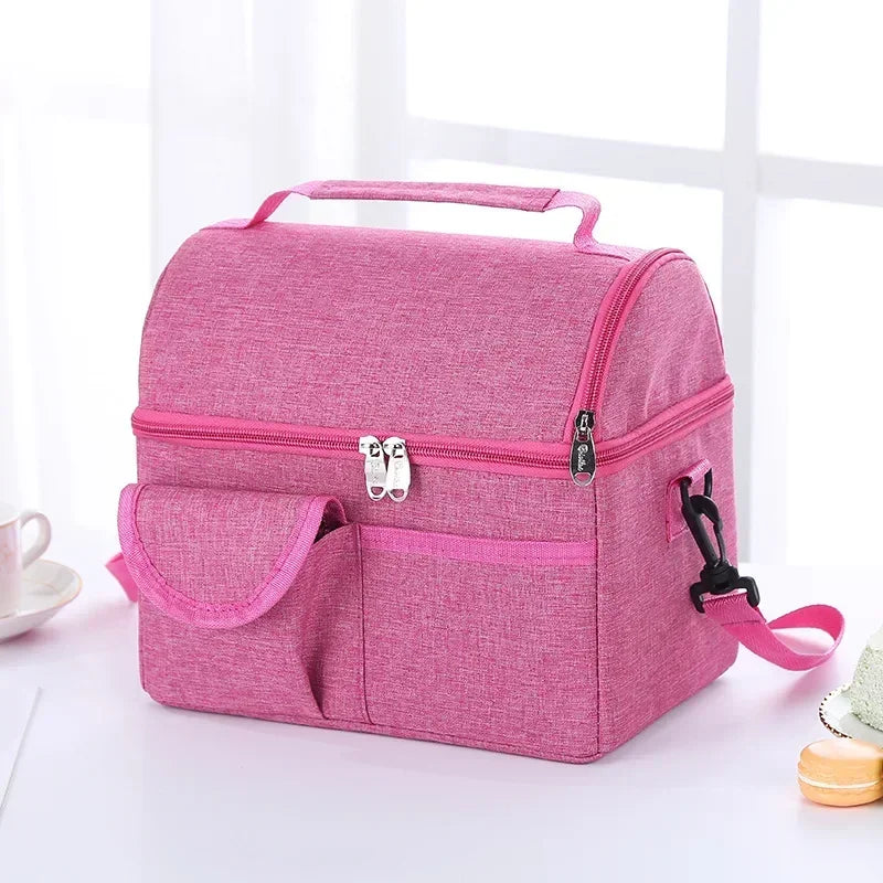 A pink insulated lunch bag with a zippered compartment and a separate pocket is shown on a white surface.