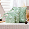 A set of three reusable light green waterproof wet bags with a floral pattern displayed on a table.