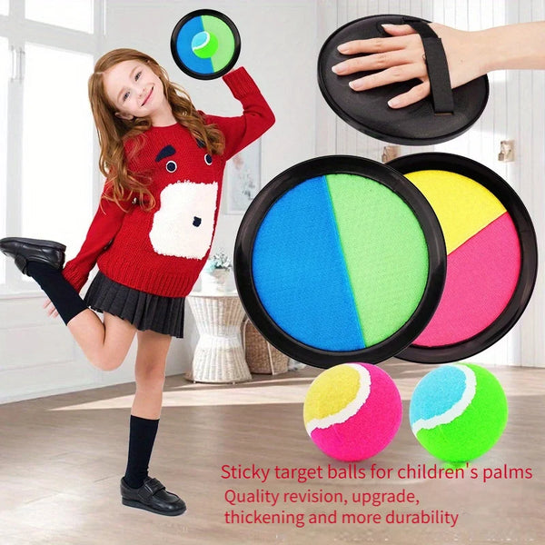 A smiling girl holds a black target ball while standing next to several colorful sticky target balls.