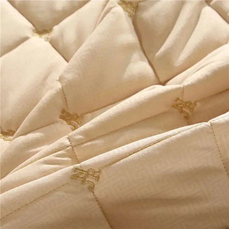 Close-up of a beige quilted bed skirt with gold embroidery.