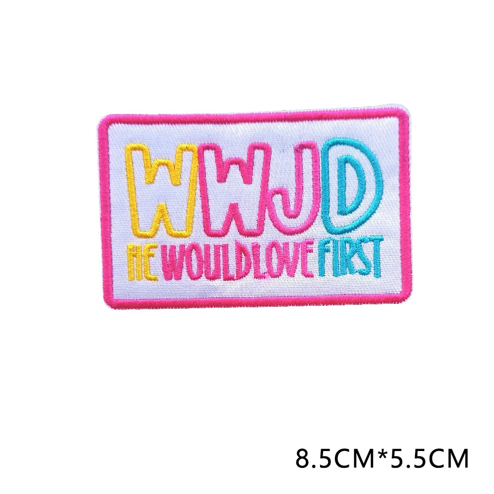 Pink embroidered patch with the letters WWJD and the text WOULD LOVE FIRST in yellow and blue thread.