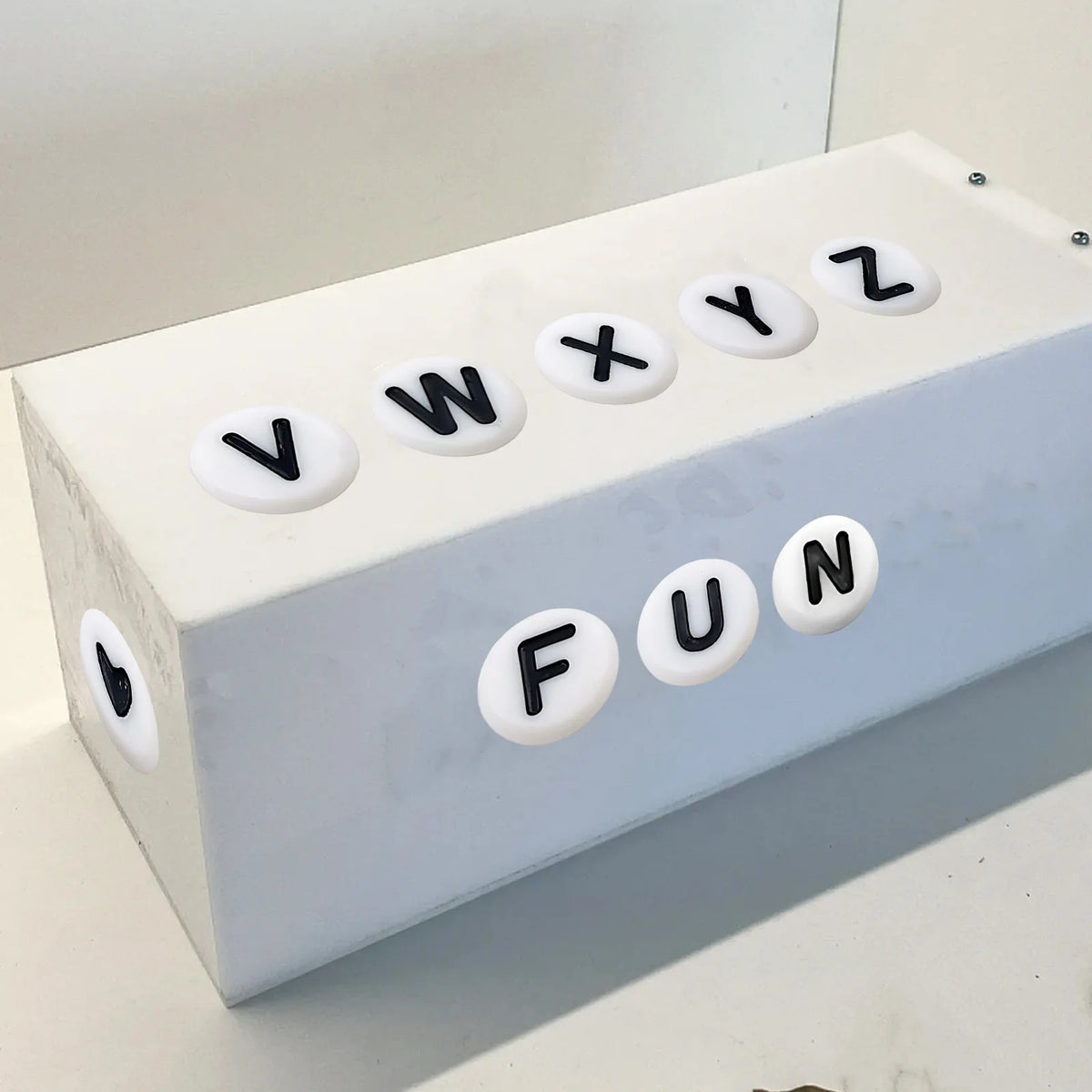 A white box with alphabet letter stickers V, W, X, Y, Z, and FUN on the lid.