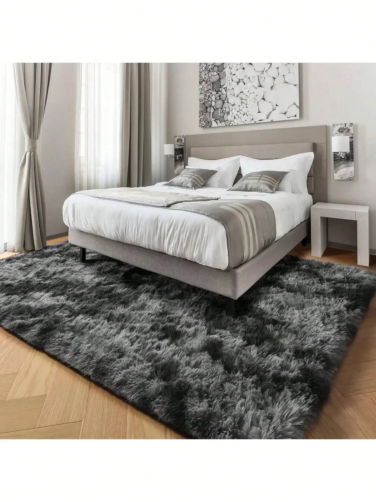 Ein flauschiger, langer Teppich in dunkelgrau und schwarz steht vor einem modernen gepolsterten Bett.