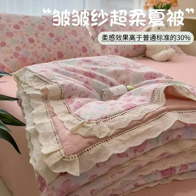 Pink floral washed cotton gauze summer quilt folded on a bed