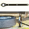 A black and gold labor-saving ratchet wrench is shown next to a tire on a wooden stand.