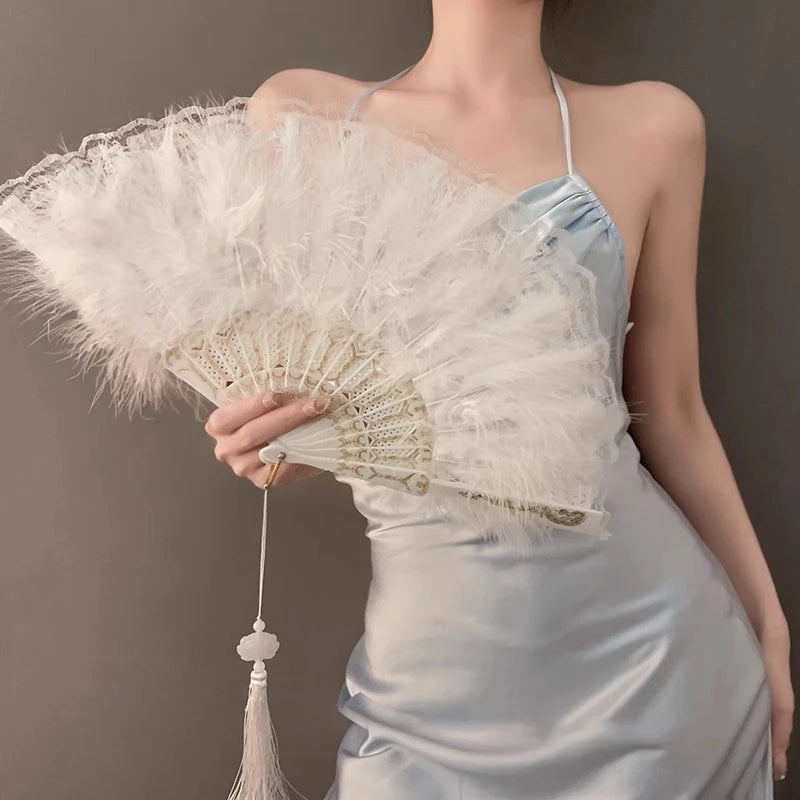 A woman holds a vintage lace-trimmed folding fan with a golden edge against a gray background.