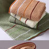 A stack of folded bath towels in various earthy tones including beige, orange, green, and brown.