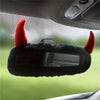 A black rearview mirror cover with red devil horns is shown in a car interior view.