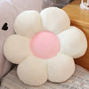 A white and pink sunflower shaped plush pillow with soft fur texture resting on a wooden surface.