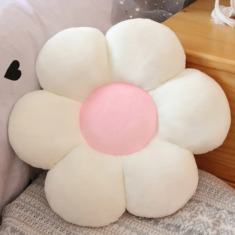 A white and pink sunflower shaped plush pillow with soft fur texture resting on a wooden surface.
