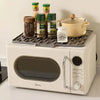 A white appliance is shown with a silicone dish drying mat holding various spice jars and a yellow pot.