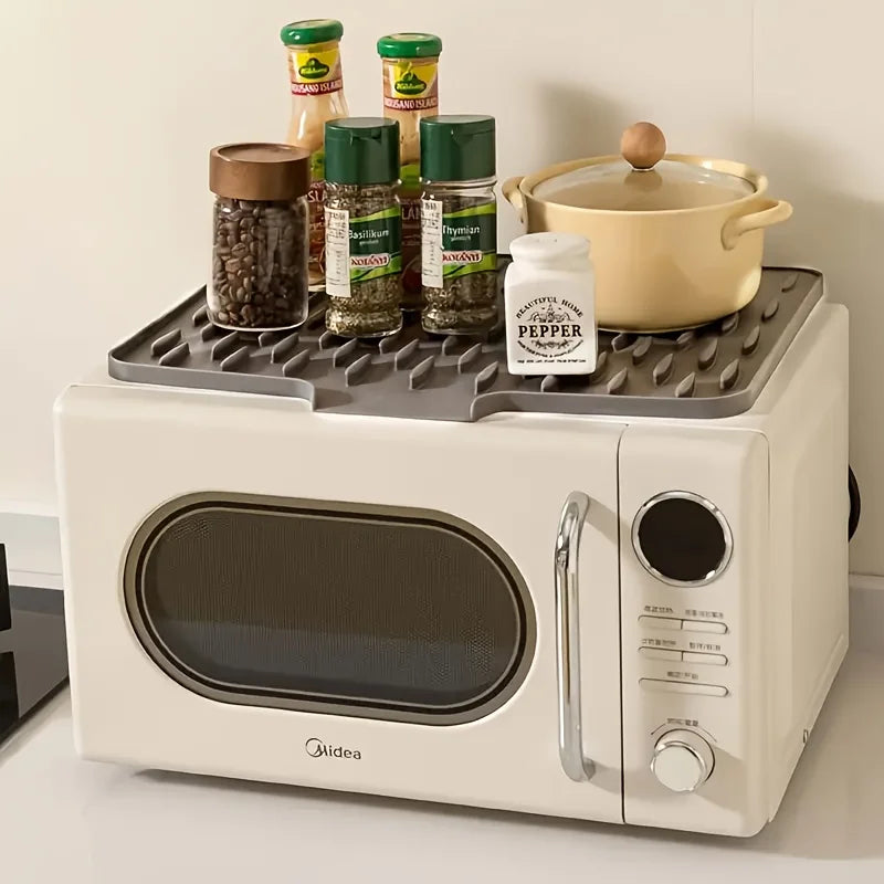 A white appliance is shown with a silicone dish drying mat holding various spice jars and a yellow pot.