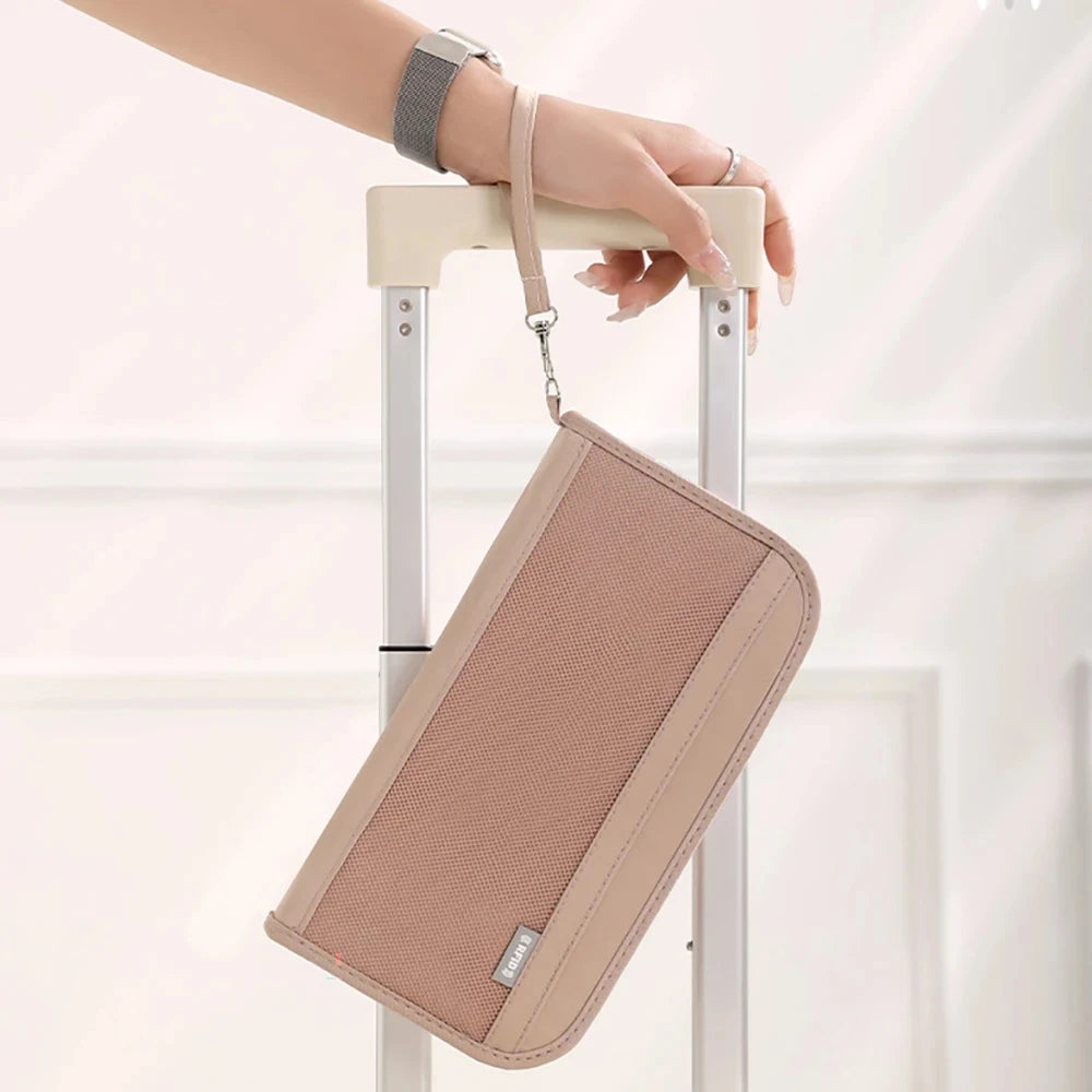 Una mano sostiene un portafotos de pasaporte beige con bloqueo RFID y una correa en un soporte de equipaje rodante blanco.