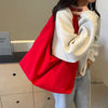A person is holding a bright red lightweight nylon tote bag over their shoulder, featuring a secure zipper closure.