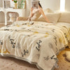 Beige Plüschdecke mit rotem Rosenmuster über einem Bett in einem hellen Raum.