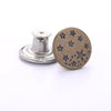 A round, bronze button with five small stars is shown next to a silver button repair kit base.