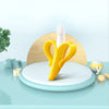 Yellow banana-shaped silicone baby teether and training toothbrush displayed on a light blue surface.