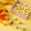 Yellow wool felt bee pompoms in a pink box surrounded by orange flowers and individual bees