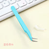 A light blue precision craft tool featuring straight and curved tips resting on a white keyboard.