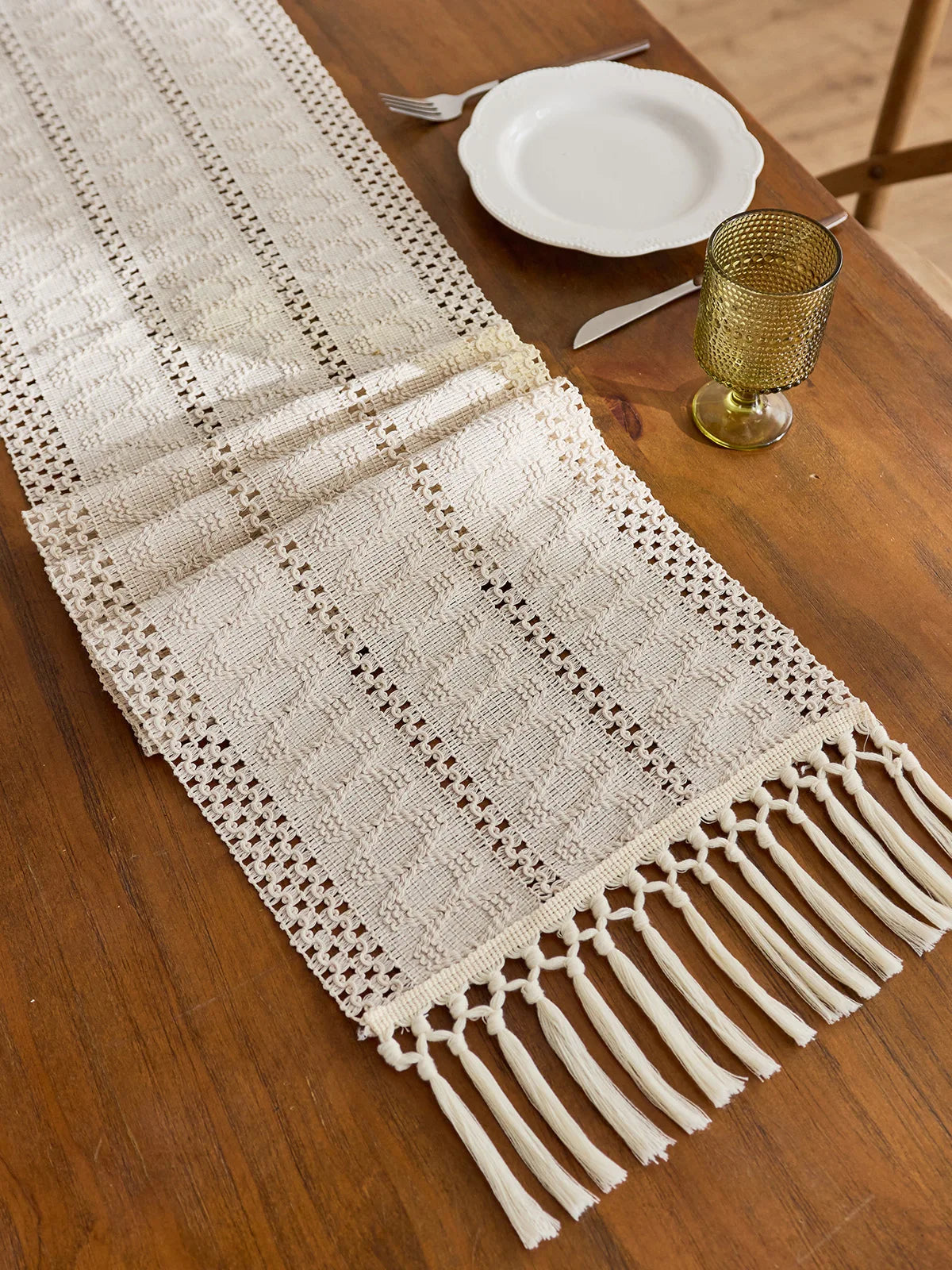 Beige boho table runner with tassels hand-woven farmhouse style placed on a wooden table.