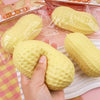 Eine Hand presst ein gelbes, weiches Dumpling-Spielzeug aus einer durchsichtigen Plastiktüte vor einem rosa Hintergrund.