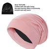 A pink silk satin sleep bonnet rolled up, showing the smooth texture and lining.