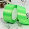 A roll of bright lime green satin ribbon for gift wrapping and crafts resting on a green card.