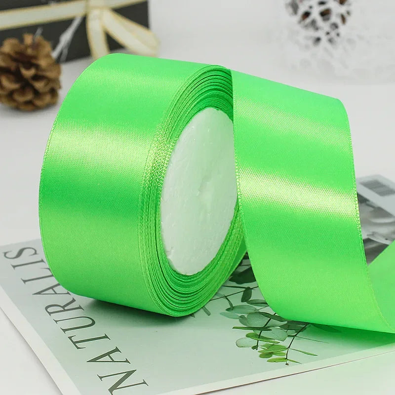 A roll of bright lime green satin ribbon for gift wrapping and crafts resting on a green card.