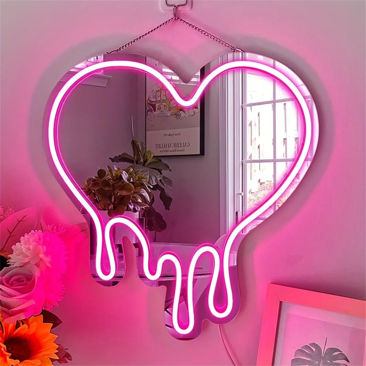 A neon sign shaped like a melting heart is mounted on a pink wall, reflecting the room and decor.