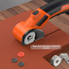 An orange cordless rotary scissor tool with a black handle and silver blade resting on a brown mat.