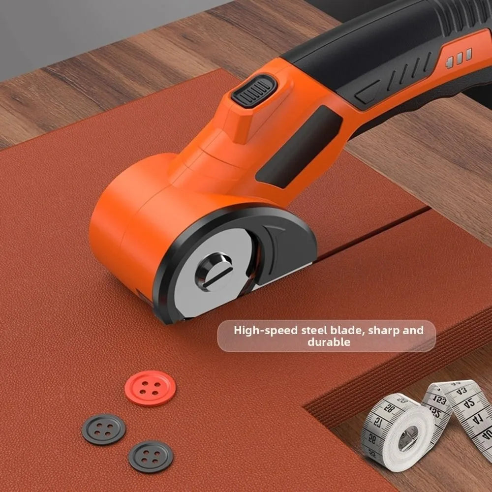An orange cordless rotary scissor tool with a black handle and silver blade resting on a brown mat.