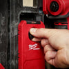 A hand is using a red Milwaukee PACKOUT magnetic bin for tool storage.