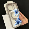 A hand holds a blue lily patterned magnetic phone case with a matte clear finish.
