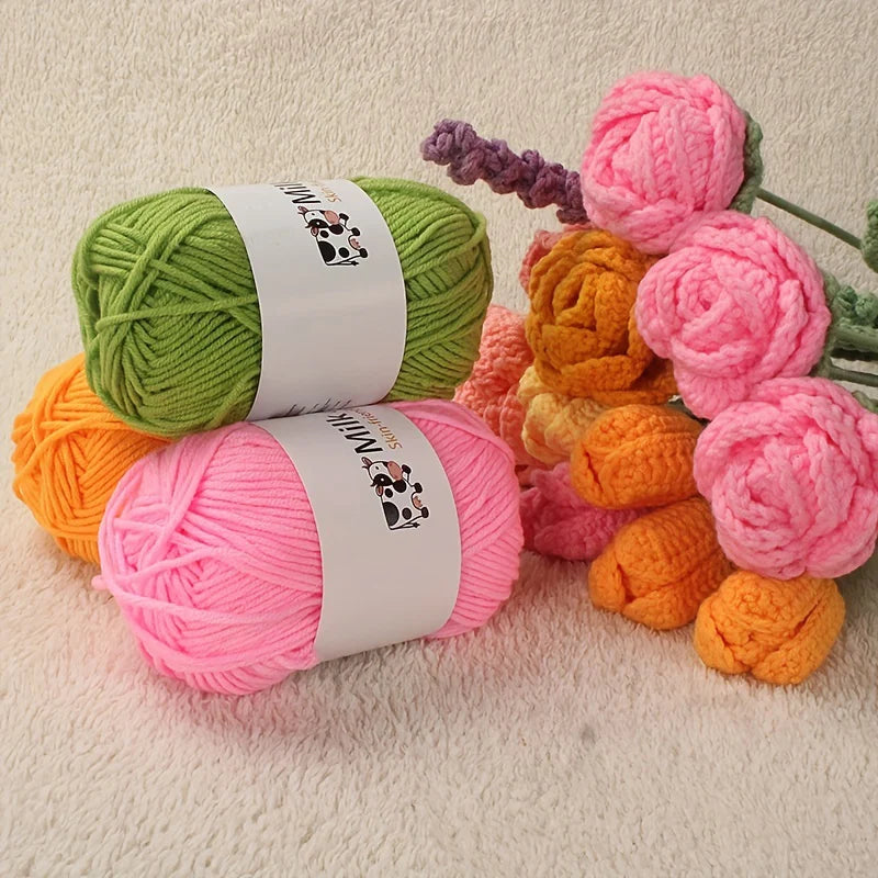A collection of pink, green, orange, and purple acrylic yarn skeins and balls for knitting and crochet projects.