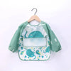A light green waterproof long-sleeve baby feeding smock with a pattern of blue sea creatures.