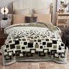 A beige weighted plush blanket is displayed on a bed with white linens and pillows.