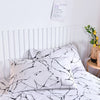 White fitted bed sheet with a black marble print pattern on a bed.