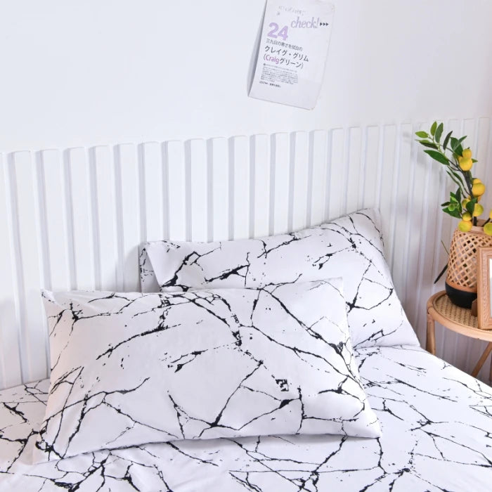 White fitted bed sheet with a black marble print pattern on a bed.