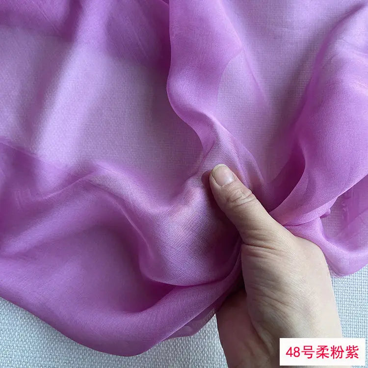 Close-up of light purple silk chiffon fabric draped and held by a hand