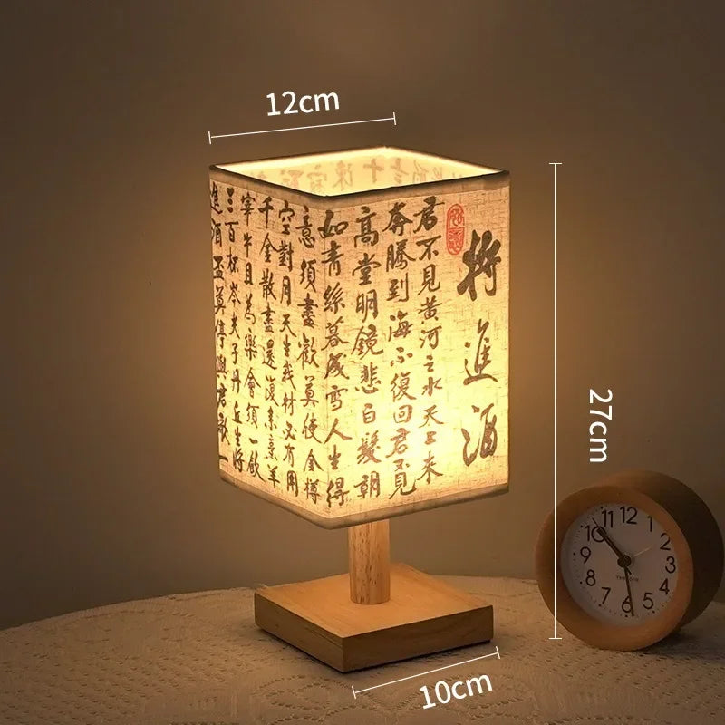 A square Chinese style table lamp with a woven linen shade sits on a wooden base, illuminated by warm light.