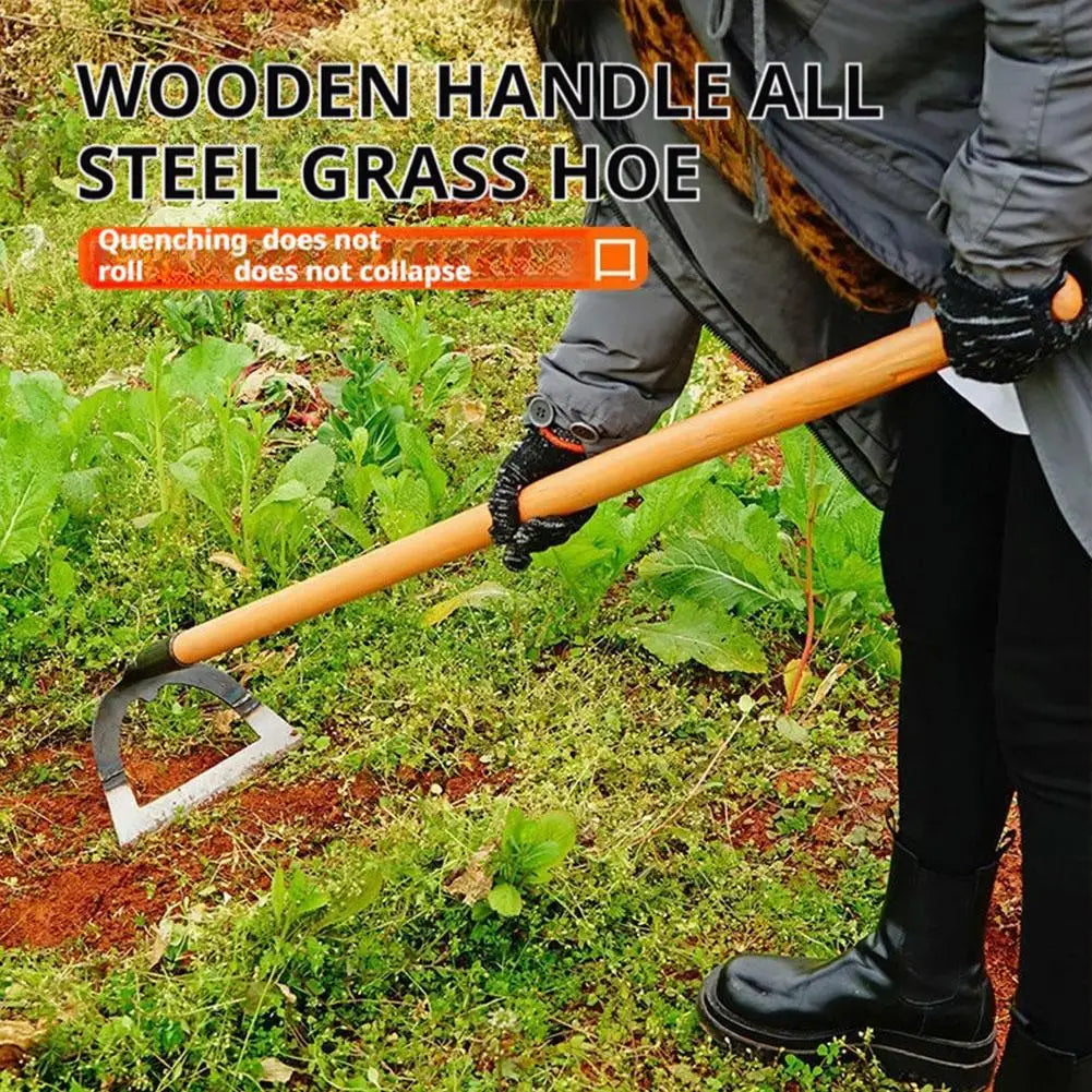 A person holds a wooden handle steel grass hoe for weeding in a garden setting.